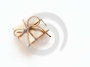 A present or gift box wrapped by rough brown recycled paper and tied with brown hemp rope as ribbon isolated on white background w