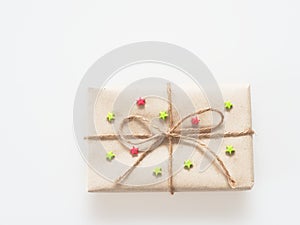 A present or gift box wrapped by rough brown recycled paper and tied with brown hemp rope as ribbon with red and green star isola