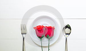 Present gift with red rose flower and dish and spoon and fork on wooden table