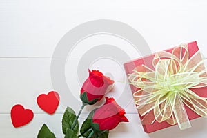 Present gift with red rose flower and gift box with bow ribbon and heart shape on wooden table