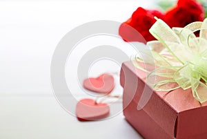 Present gift with red rose flower and gift box with bow ribbon and heart on wooden table