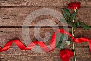 Present for St. Valentines Day - Red rose with ribbon on dark wooden background copyspace