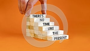 Present time symbol. Concept words There is no time like the present on wooden block. Beautiful orange table orange background.