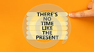Present time symbol. Concept words There is no time like the present on wooden stick. Beautiful orange table orange background.