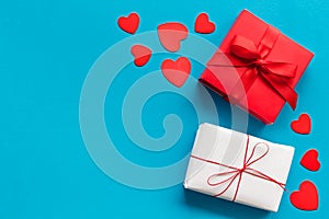 Present to a lover on Valentine`s Day. Gift boxes near paper hearts on blue background top-down frame copy space