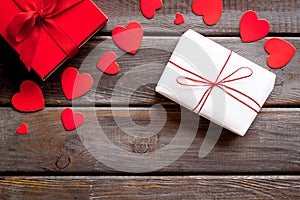 Present to a lover on Valentine`s Day. Gift boxes near paper hearts on dark wooden background top-down frame copy space