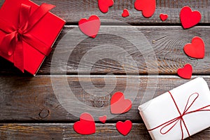 Present to a lover on Valentine`s Day. Gift boxes near paper hearts on dark wooden background top-down frame copy space