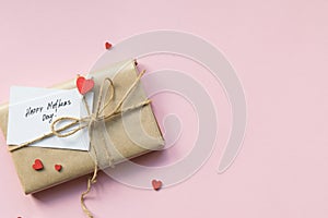 Present wrapped in brown craft paper and tie hemp string on Light pink background. Gift box with greetings on Mothers