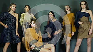 Presentation of clothing collection, fashion photo shoot with beautiful female models posing on background of dark wall