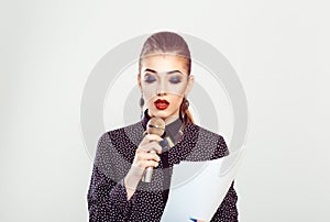 Presenter, girl having speech presentation. Business woman speaker speaking at microphone mic reading from papers isolated on