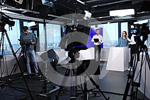 Presenters, makeup artist and camera operator working in studio. News broadcasting