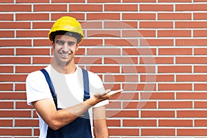 Presenting young worker in front of a brick wall