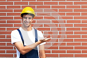 Presenting young worker in front of a brick wall photo