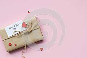 Presents wrapped in brown craft paper and tie hemp string on Light pink background. Gift box with greetings on Mothers Day. Top