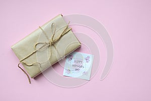 Presents wrapped in brown craft paper and tie hemp string on Light pink background. Gift box with greetings on Mothers Day. Top