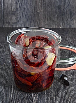 Preservation of sun-dried tomatoes with herbs in olive oil in a glass jar