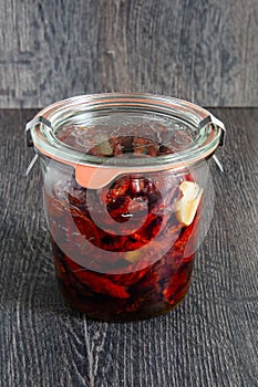 Preservation of sun-dried tomatoes with herbs in olive oil in a glass jar