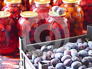 Preservation for the winter is in the pantry or cellar. A box with a blue plum on a background of finished compote in large glass