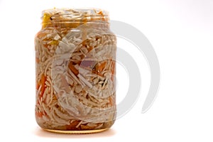 Preserved cabbage and red paprika salad in glass jar on a white background