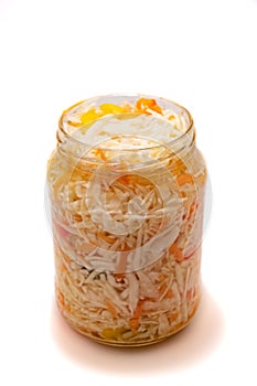 Preserved cabbage and red paprika salad in glass jar on a white background