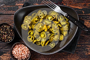 Preserved Jalapenos, pickled and sliced in plate . Dark Wooden background. Top view