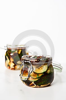 Preserved and marinated cucumbers in jars in asian or Chinese style with soy sauce, garlic. Also includes ginger, chilli
