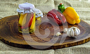 Preserved vegetarian food concept.Canned red, green an yellow peppers in a jar on wooden background