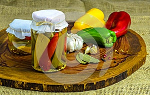 Preserved vegetarian food concept.Canned red, green an yellow peppers in a jar on wooden background