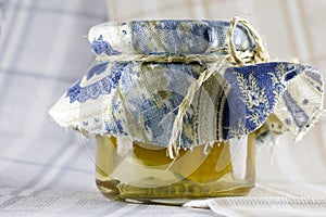 The preserves are in a jar with a decorative top