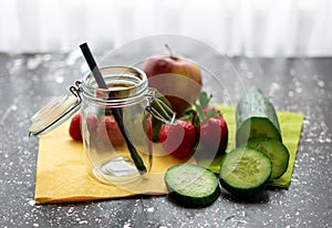 Preserving jar surrounded by fresh fruit and a cucumber