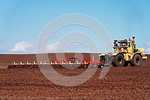 Presowing tillage. Tractor with trailed combination cultivator in the field. Copy space.