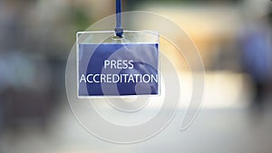 Press accreditation pass against blurred background, media ID card during event photo