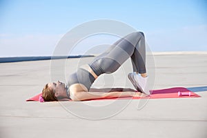 Press and buttocks exercises. Young sportive woman keeping body with, training on warm sunny day outdoor