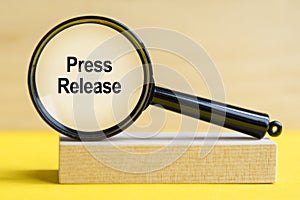 Press Release word through magnifying glass on wooden background