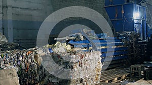 Press at waste recycling plant for pressing plastic and cardboard waste, processing