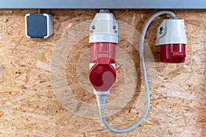 On a pressboard mounted 220 volts and two 380 volt sockets in a factory hall, red and white