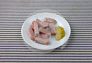 Pressed pork canned meat chunks on a plate with mustard.