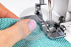 Presser foot of sewing machine with needle and thread close up. Detail of sewing machine with female fingers. Women`s hands sewin