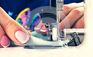 Presser foot of sewing machine with needle and thread close up. Detail of sewing machine with female fingers. Women`s hands sewin