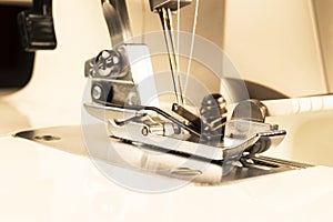 Presser foot of sewing machine with needle and thread close up. Detail of sewing machine. The sewing machine`s foot with a needle