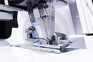 Presser foot of sewing machine with needle and thread close up. Detail of sewing machine. The sewing machine`s foot with a needle