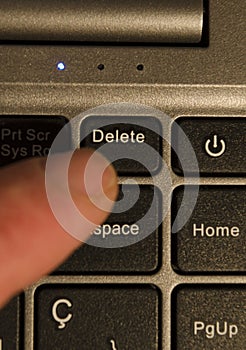 pressing delete key on laptop. finger pressing delete key