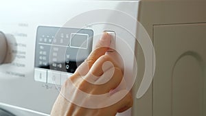 Pressing the start button on the washing machine close-up
