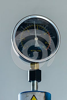 Pressure gage on an industrial press with a greasy look suggesting workshop tools