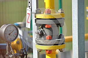 Pressure gauge for measuring the pressure of natural gas in a gas pipeline. Yellow transport pipes on the surface of the fence.