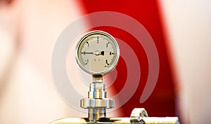 Pressure gauge psi meter in pipe and valves of water system industrial focus left closeup white light defocus blur background