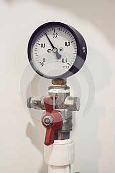 Pressure gauge and water filter close-up against a white wall in a private home