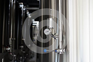 Pressure on pressure gauge on industrial machine in factory. Modern Beer Factory. Steel tanks for beer fermentation and