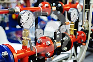 Pressure sensors in the urban heating system. Hot water pipes in an industrial boiler room. Mechanical barometer with arrow to