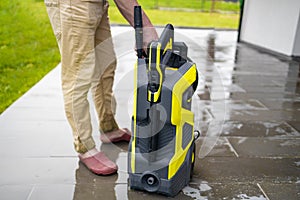 Pressure washer cleaning machine on wet concrete floor near the house build, cleaning terrace with a power washer